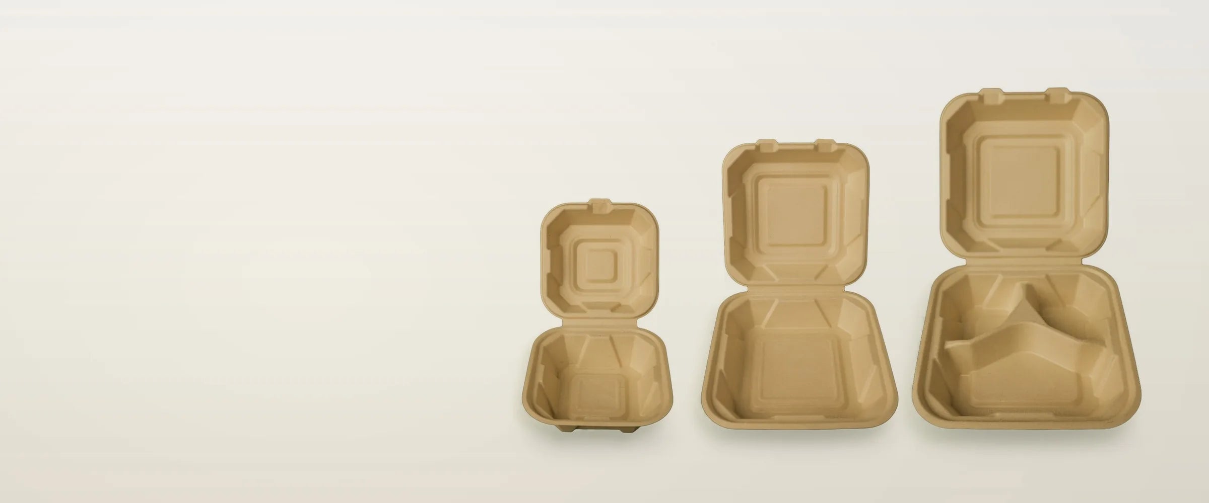 Three open bagasse clamshells, 6, 8 and 9 inch, on a cream table
